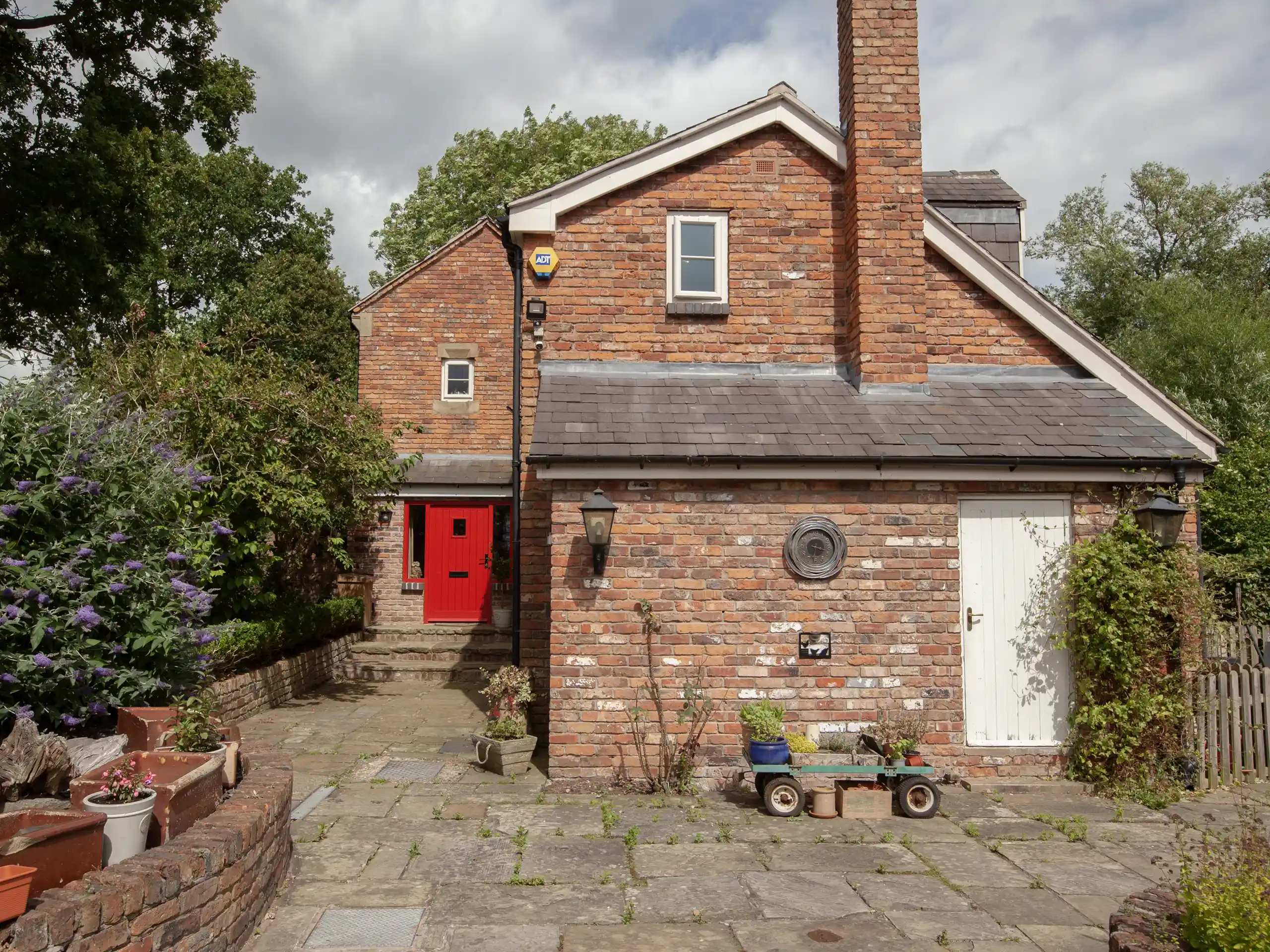 Brick cottage front garden design featuring plants and rustic path