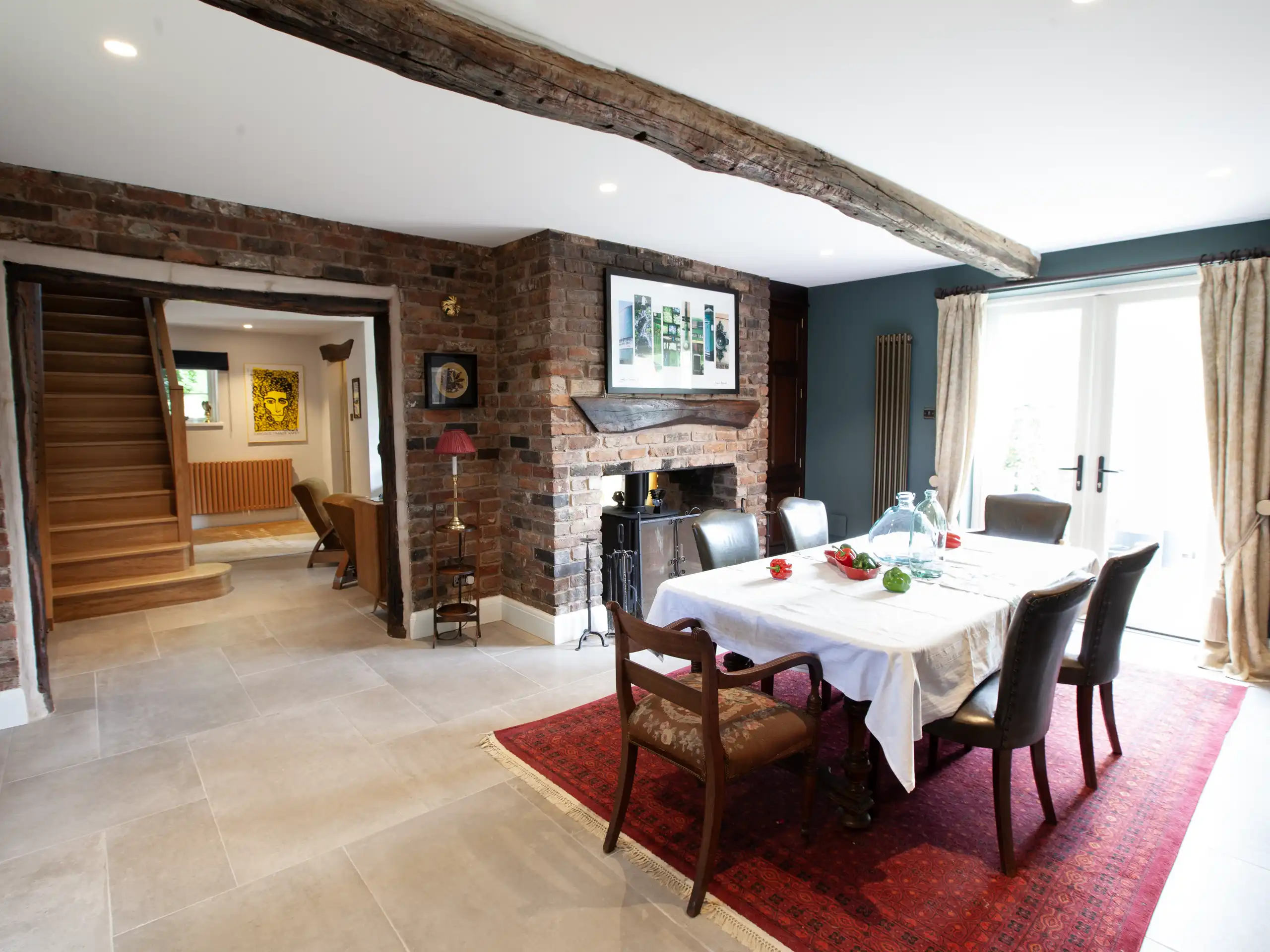 Open-plan dining and living area with exposed brick walls and wooden beams.
