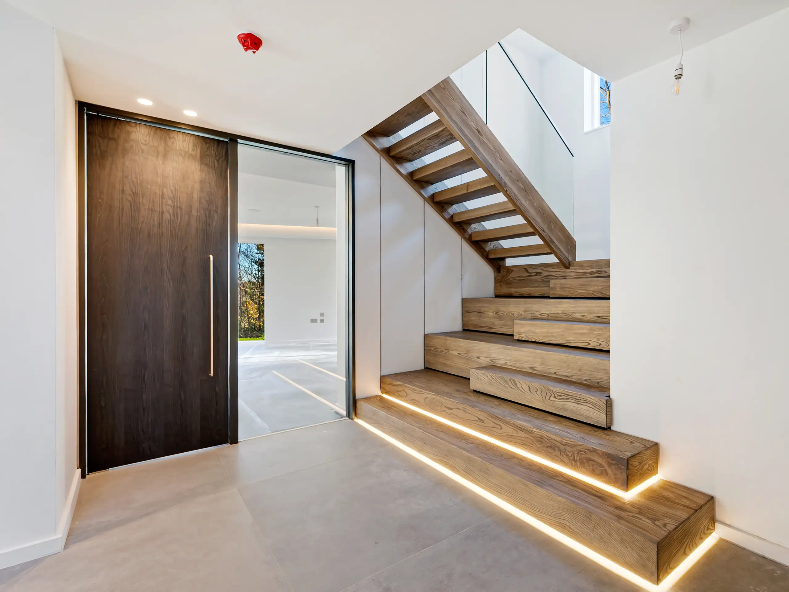 Modern entrance featuring a bespoke staircase with integrated lighting at Waterbank, Prestbury.