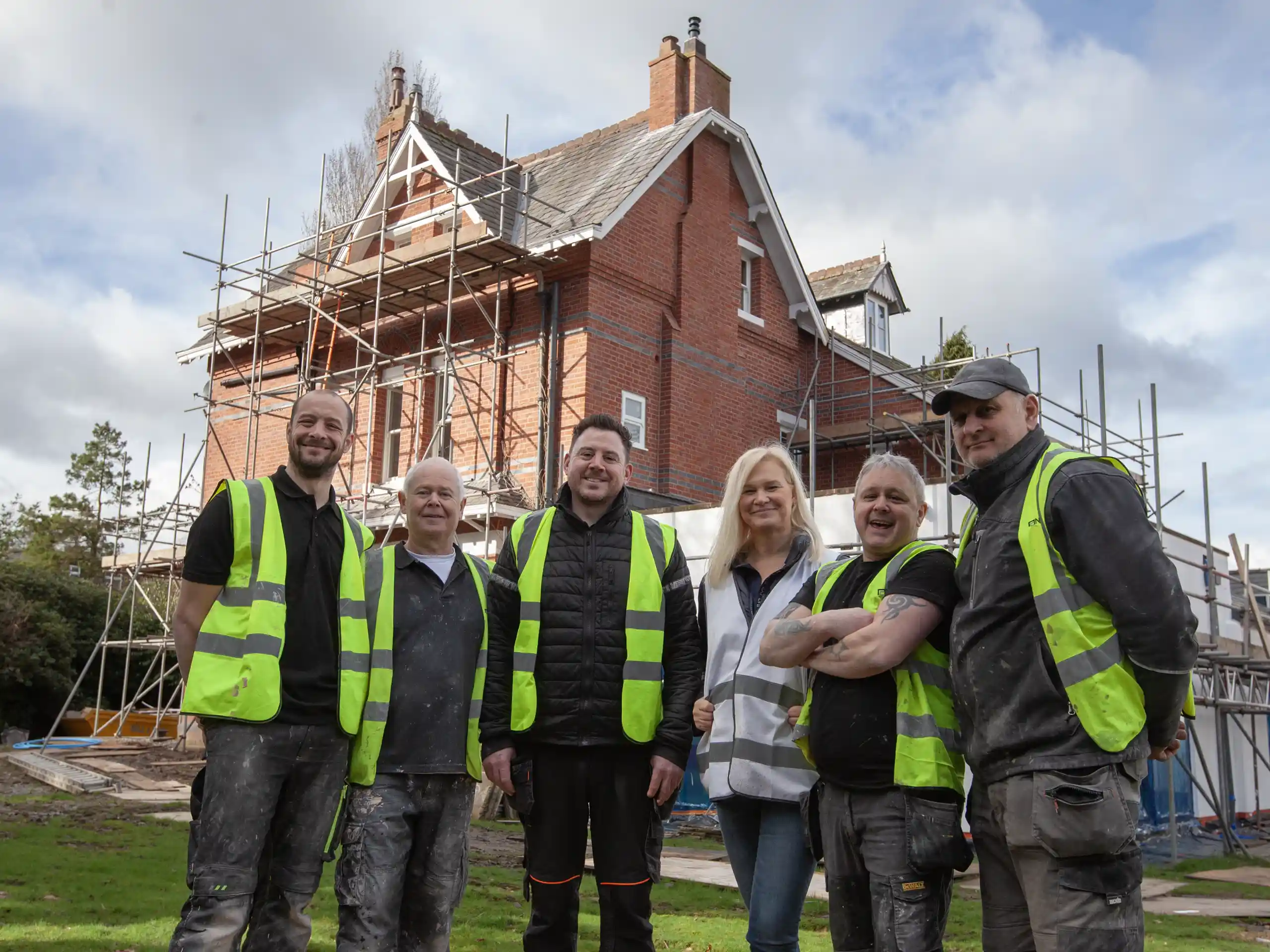 Elena standing with her construction team in front of a restored home in Wilmslow Cheshire