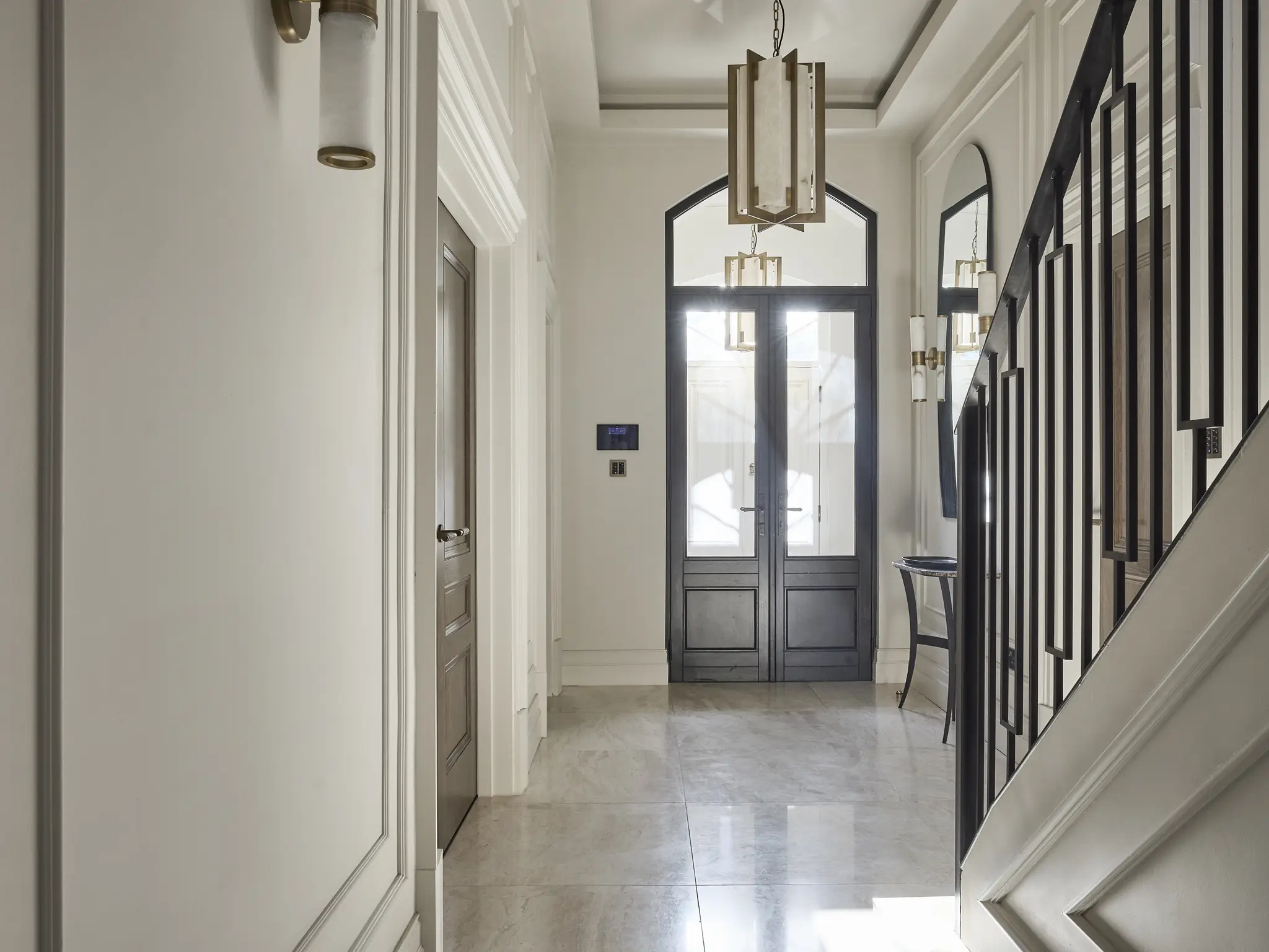 Elegant hallway with bespoke panelling, marble flooring, and gold-accented lighting in the Westwood project, Wilmslow.