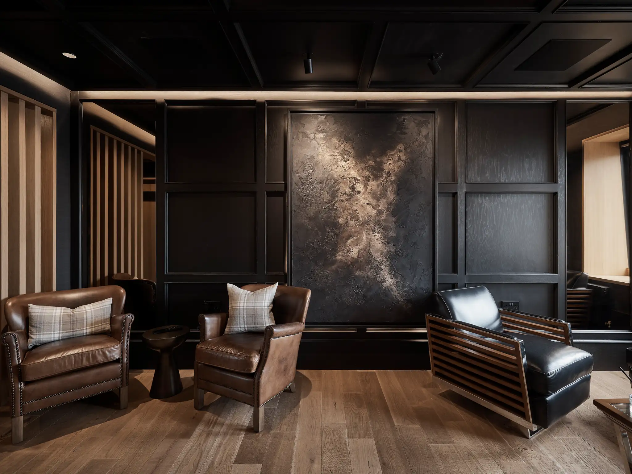 Feature black textured wall with leather chairs and artwork